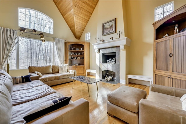 living room with a towering ceiling, a wealth of natural light, light hardwood / wood-style floors, and wooden ceiling