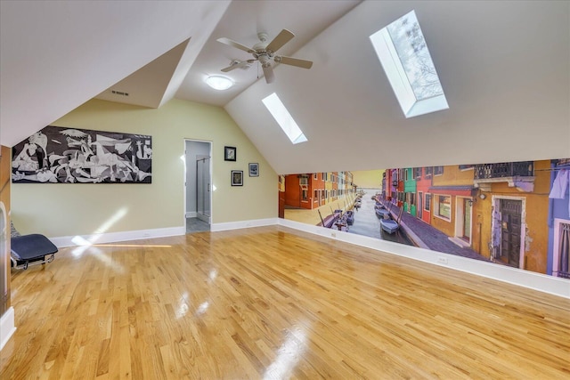 interior space featuring ceiling fan, wood-type flooring, and lofted ceiling with skylight