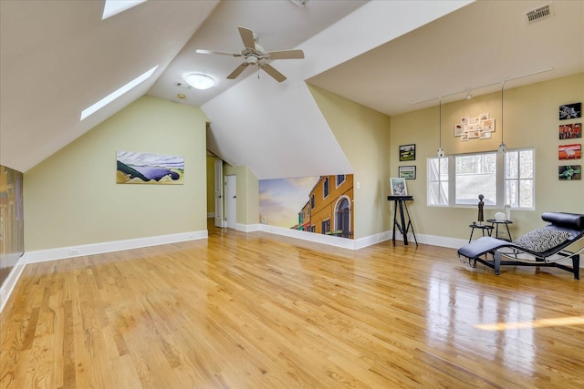 unfurnished living room featuring ceiling fan, lofted ceiling with skylight, and hardwood / wood-style flooring