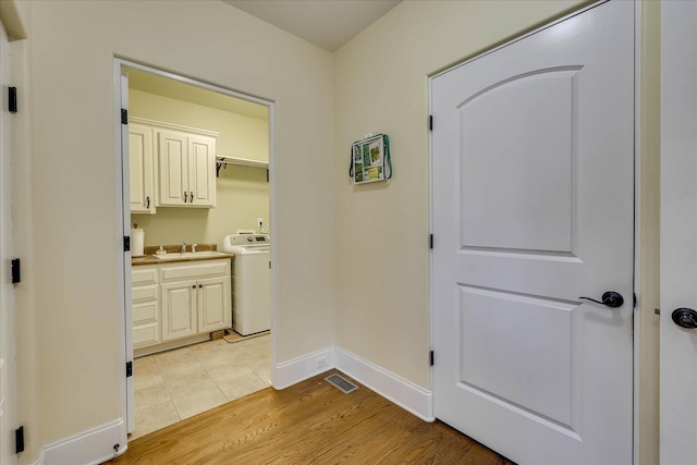 hallway with washer / dryer, light hardwood / wood-style floors, and sink