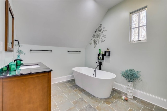 bathroom featuring a bathing tub, lofted ceiling, and vanity