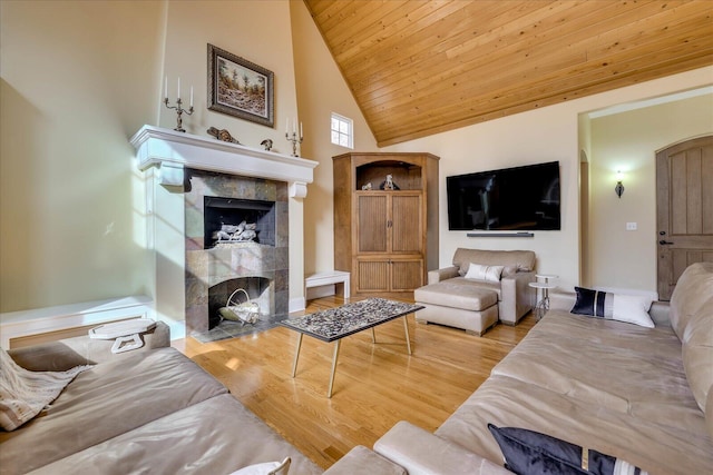 living room with light wood-type flooring, wood ceiling, a fireplace, and high vaulted ceiling