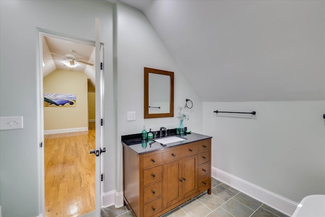 bathroom with ceiling fan, vanity, vaulted ceiling, and tile patterned flooring