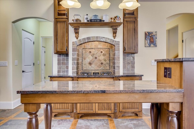 kitchen featuring decorative light fixtures, backsplash, stone counters, and black gas stovetop