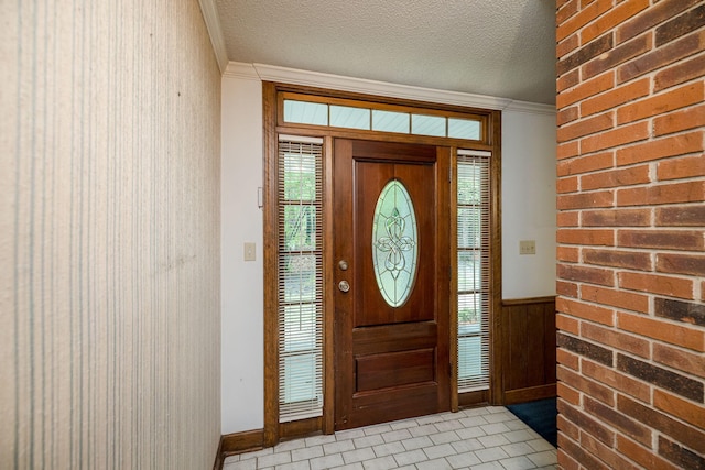 foyer featuring light tile patterned flooring, a textured ceiling, and ornamental molding