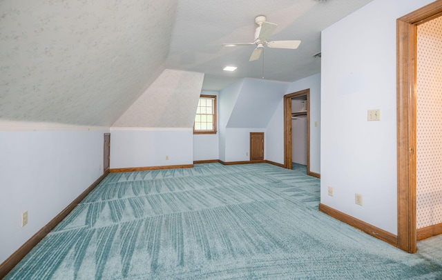 additional living space with a textured ceiling, light colored carpet, vaulted ceiling, and ceiling fan