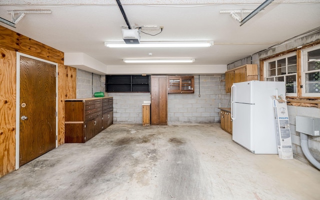 garage featuring white refrigerator and a garage door opener