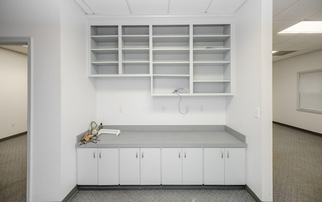 bar with a paneled ceiling and white cabinetry