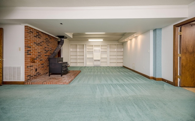 basement featuring carpet flooring, a wood stove, and crown molding