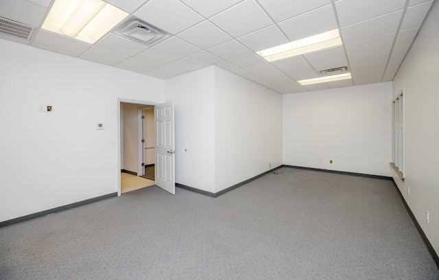 carpeted empty room featuring a drop ceiling