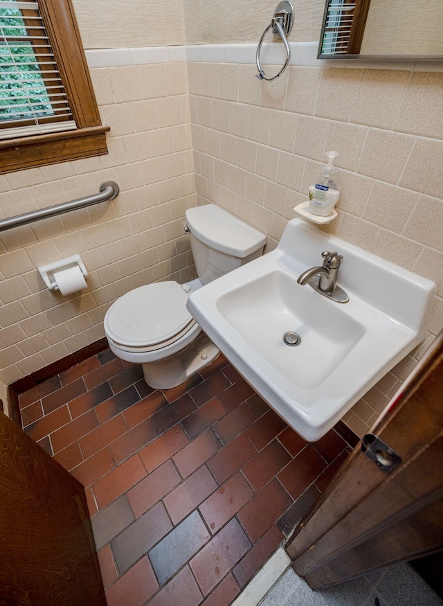 bathroom with sink, toilet, and tile walls