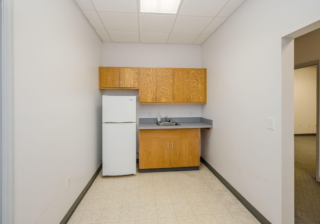 kitchen with white fridge, a drop ceiling, and sink