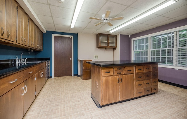 kitchen featuring ceiling fan, a kitchen island, a drop ceiling, and sink