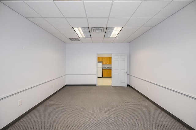 carpeted empty room with a drop ceiling