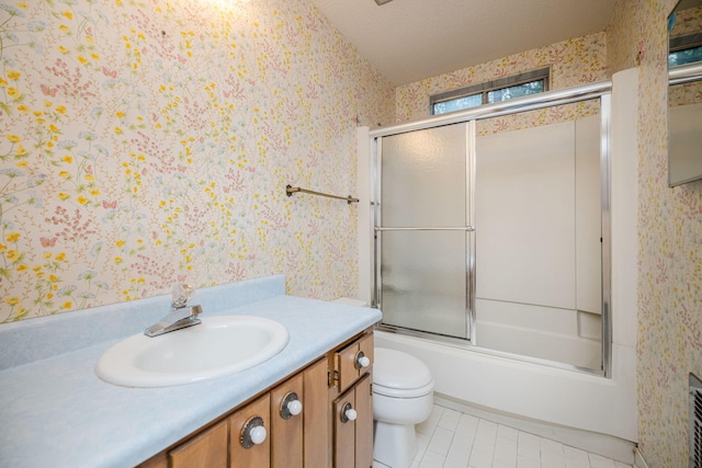 full bathroom featuring vanity, combined bath / shower with glass door, tile patterned flooring, toilet, and a textured ceiling