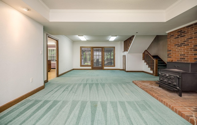 unfurnished living room featuring carpet flooring, a wood stove, crown molding, and a tray ceiling