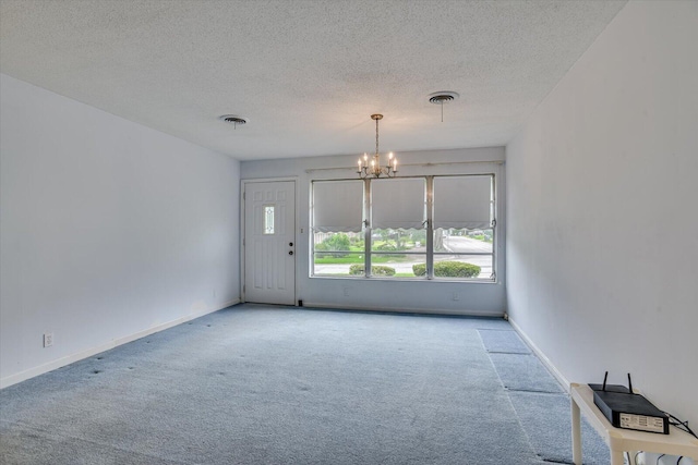 spare room with a textured ceiling, a notable chandelier, and light carpet