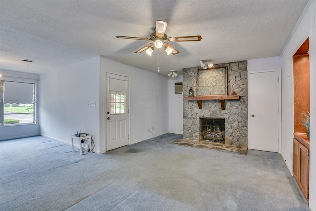 unfurnished living room with carpet flooring, ceiling fan, a fireplace, and a textured ceiling