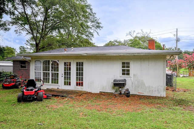 rear view of property featuring french doors and a lawn