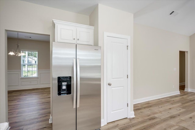 4921 Mossycup Ct, Hephzibah, GA 30815 - kitchen featuring stainless steel fridge with ice dispenser, light wood-style floors, a chandelier, white cabinetry, and a wainscoted wall