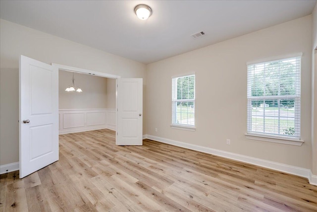 4921 Mossycup Ct, Hephzibah, GA 30815 - empty room featuring light wood-type flooring, a chandelier, and wainscoting
