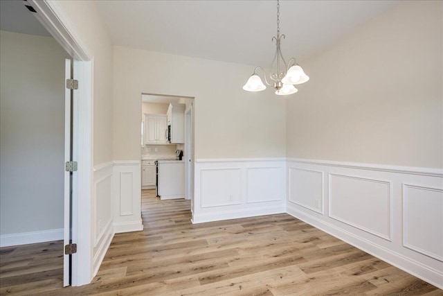4921 Mossycup Ct, Hephzibah, GA 30815 - unfurnished dining area featuring a chandelier, a wainscoted wall, light wood-style floors, and a decorative wall