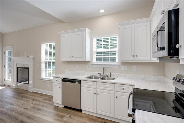 4921 Mossycup Ct, Hephzibah, GA 30815 - kitchen with stainless steel appliances, white cabinetry, light wood-type flooring, a fireplace, and light stone counters