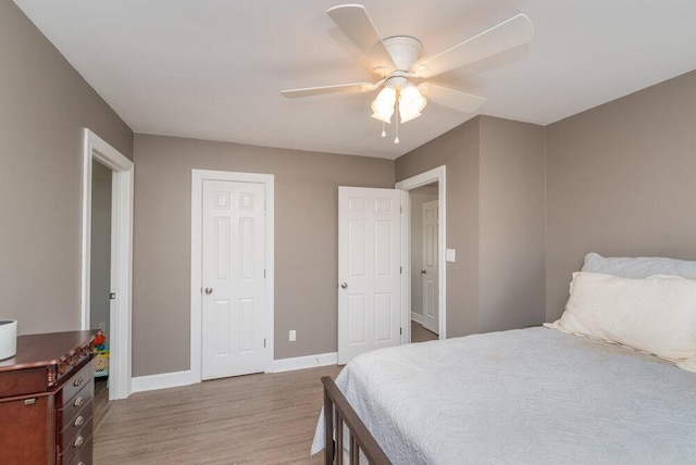 bedroom with a ceiling fan, wood finished floors, and baseboards