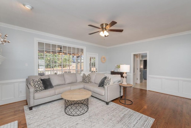 living room featuring wood finished floors, a ceiling fan, and ornamental molding