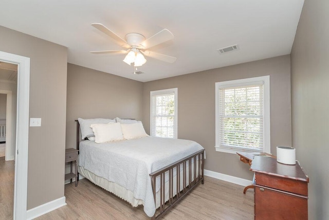 bedroom with visible vents, light wood-style flooring, a ceiling fan, and baseboards