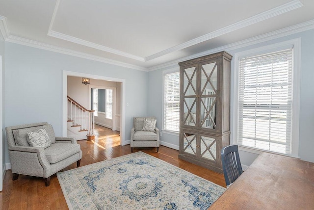 sitting room with a wealth of natural light, stairway, crown molding, and wood finished floors