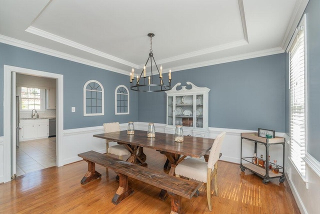 dining space with wood finished floors, a chandelier, wainscoting, and crown molding