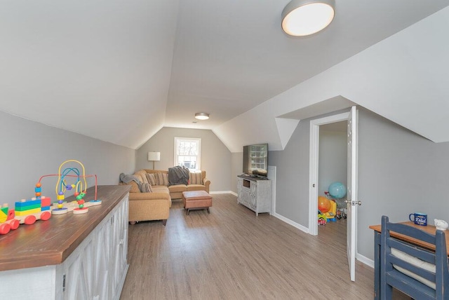 living room featuring baseboards, lofted ceiling, and light wood-style flooring