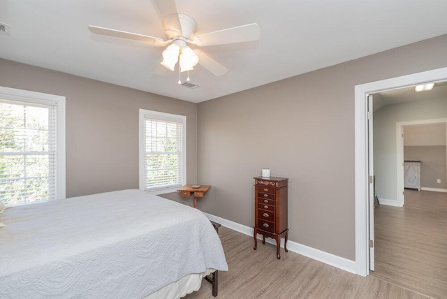 bedroom featuring baseboards, multiple windows, and light wood finished floors