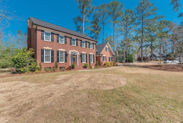 colonial house with a front lawn and brick siding