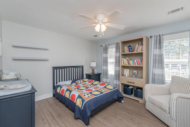 bedroom featuring baseboards, visible vents, light wood finished floors, and ceiling fan