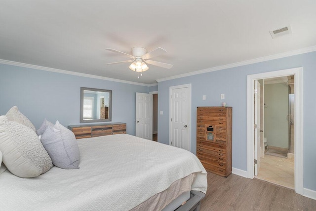 bedroom with visible vents, baseboards, wood finished floors, and crown molding