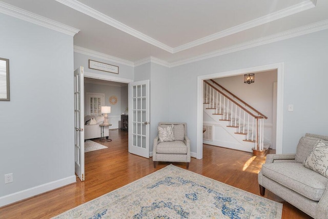 sitting room with stairway, wood finished floors, baseboards, french doors, and crown molding