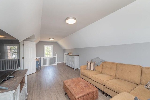 living area with light wood-style flooring, baseboards, and vaulted ceiling