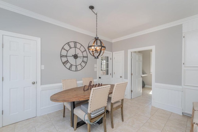 dining space with a notable chandelier, a wainscoted wall, light tile patterned floors, and ornamental molding