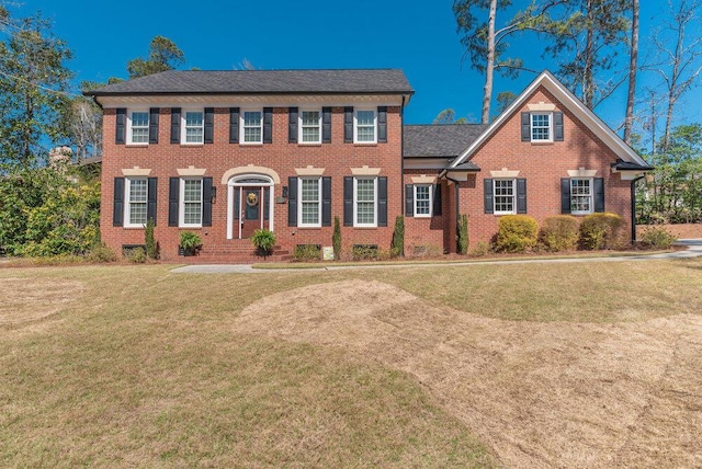 colonial-style house with brick siding and a front yard