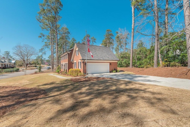 view of side of property featuring a garage, brick siding, and driveway