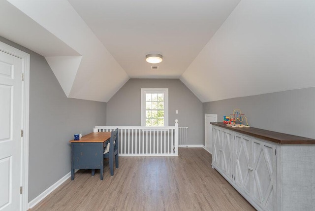 office with visible vents, baseboards, light wood-style floors, and vaulted ceiling