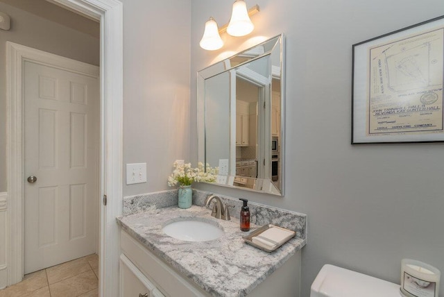 half bath featuring tile patterned flooring, toilet, and vanity