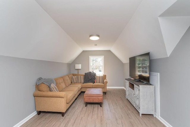 living area featuring lofted ceiling, baseboards, and light wood-type flooring