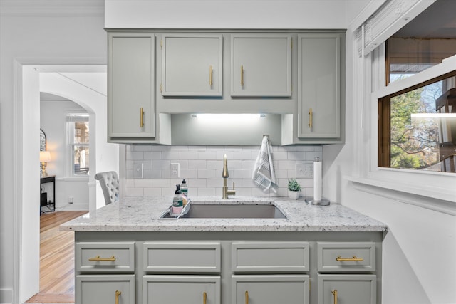 1738 Kissingbower Rd, Augusta, GA 30904 - kitchen with gray cabinetry, backsplash, light stone counters, wood finished floors, and ornamental molding