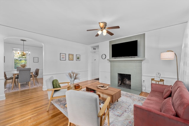 1738 Kissingbower Rd, Augusta, GA 30904 - living room featuring ceiling fan, a brick fireplace, a chandelier, light wood-type flooring, and arched walkways