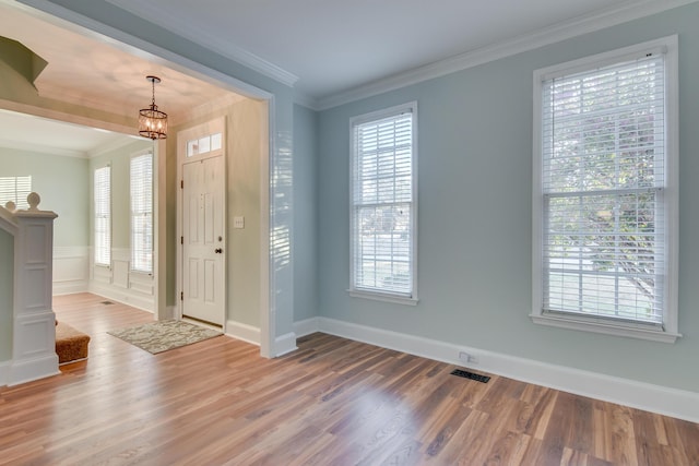 foyer featuring a notable chandelier, visible vents, ornamental molding, wood finished floors, and baseboards