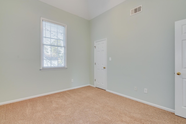 spare room with light carpet, visible vents, and baseboards