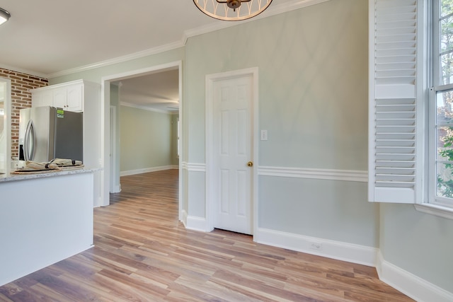 interior space with baseboards, light wood finished floors, and crown molding